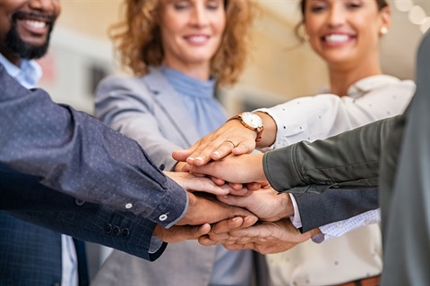 Business people standing in a circle with their hands in the center