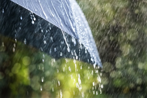 Raindrops falling off of a black umbrella