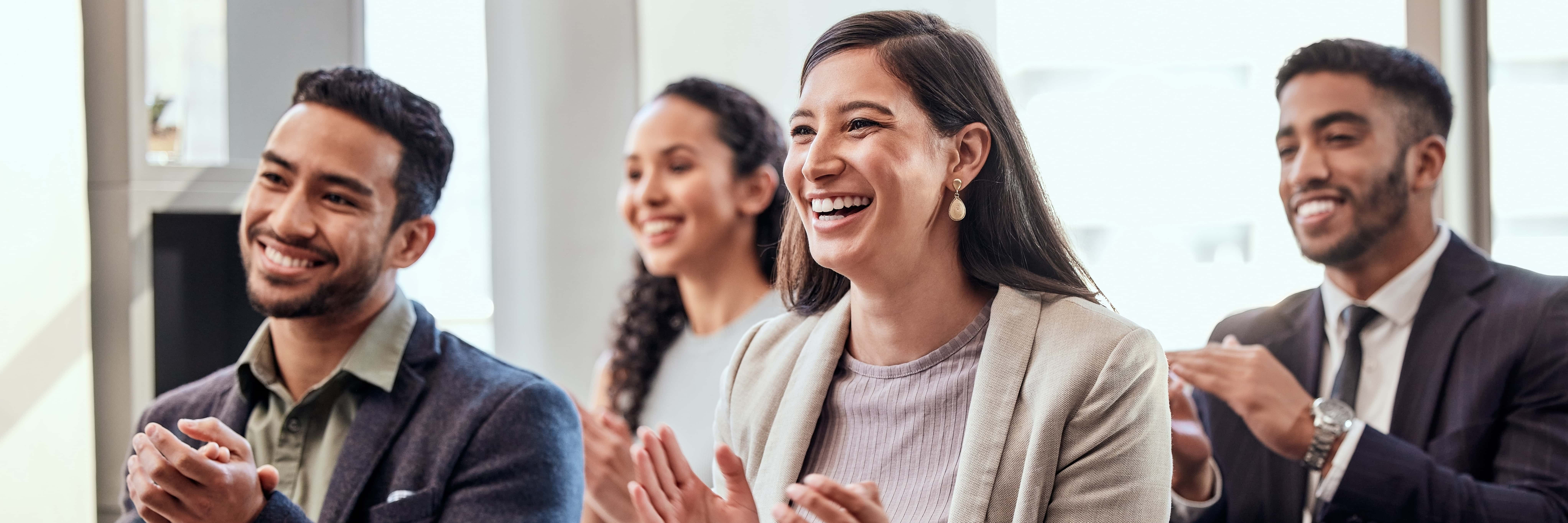 people dressed in business attire clapping and smiling 