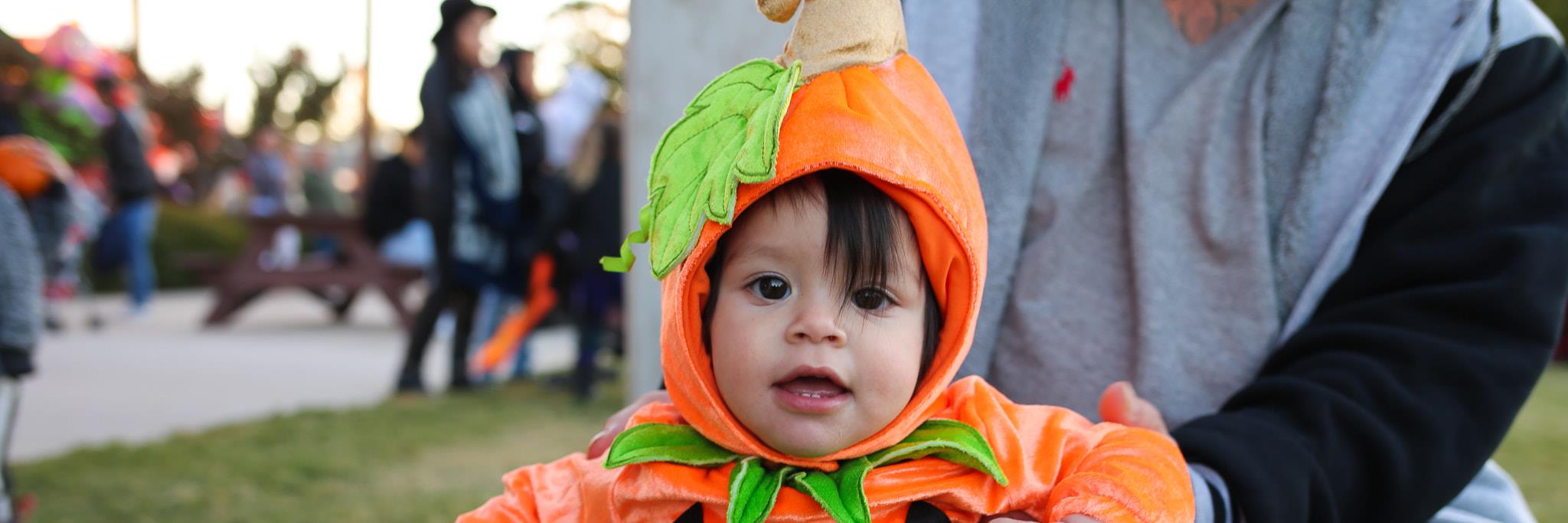 child smiling in pumpkin costume at Street n Treat event in 2019. Photo by Nikki Funderburk